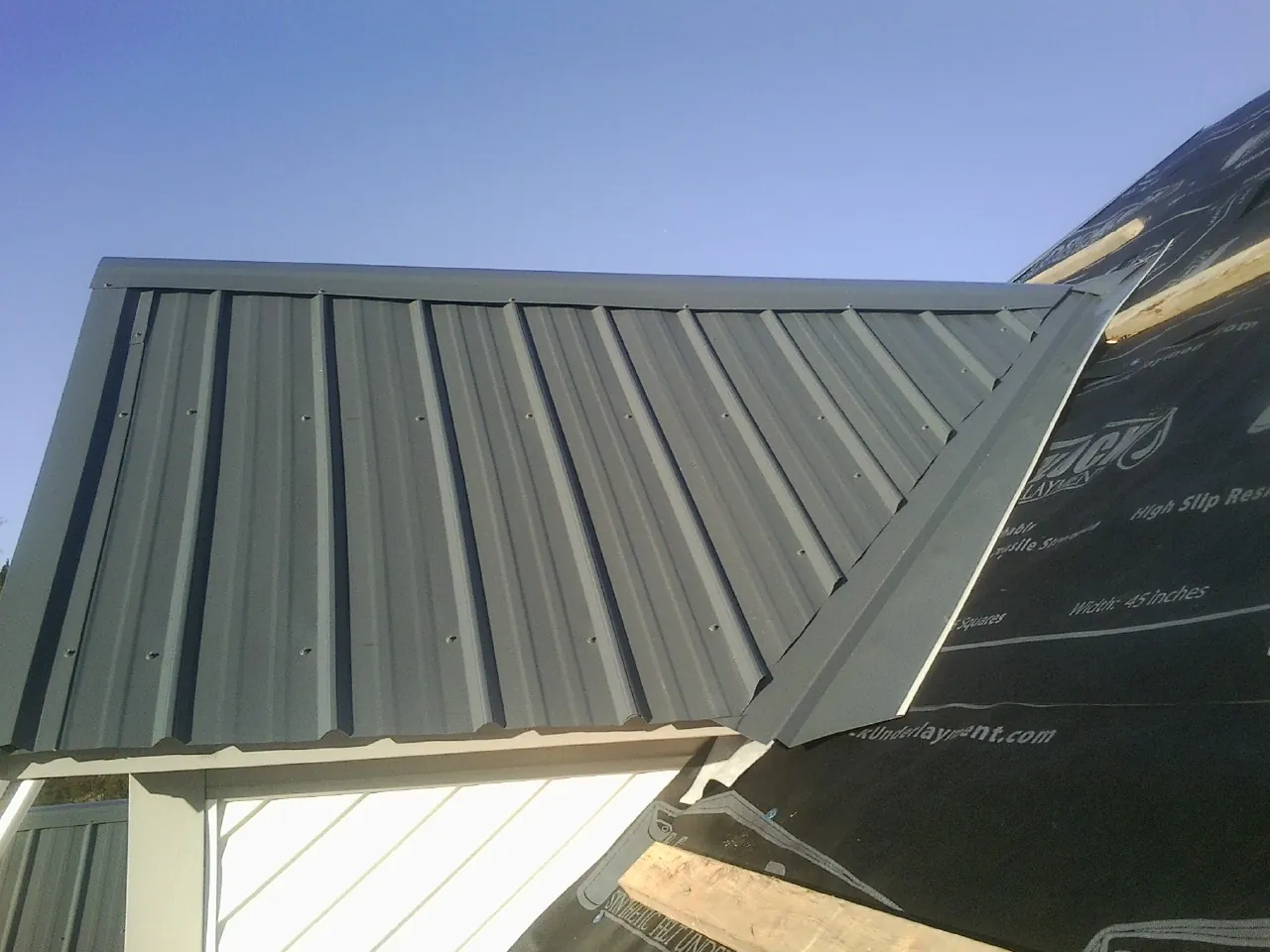 Gray metal roof panels going on over a garage gable in Staples