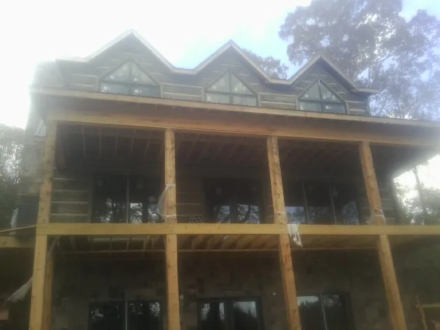 Dormers and porch framing on a large log home under construction — Roof Coating work by our crew in Staples