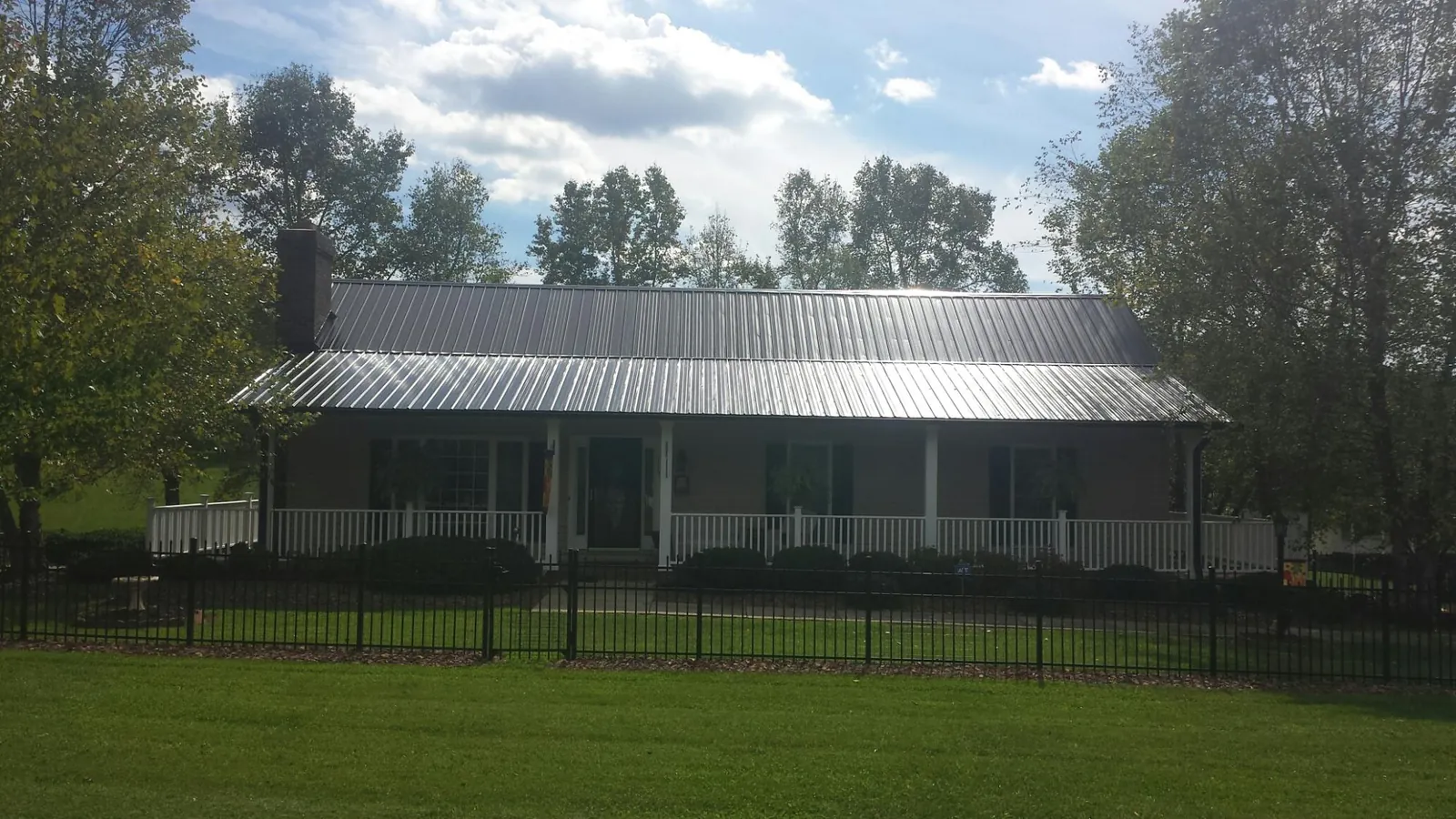 Gray metal roof on a brick ranch with a full width front porch — Gutter Guard Installation work by our crew in Staples