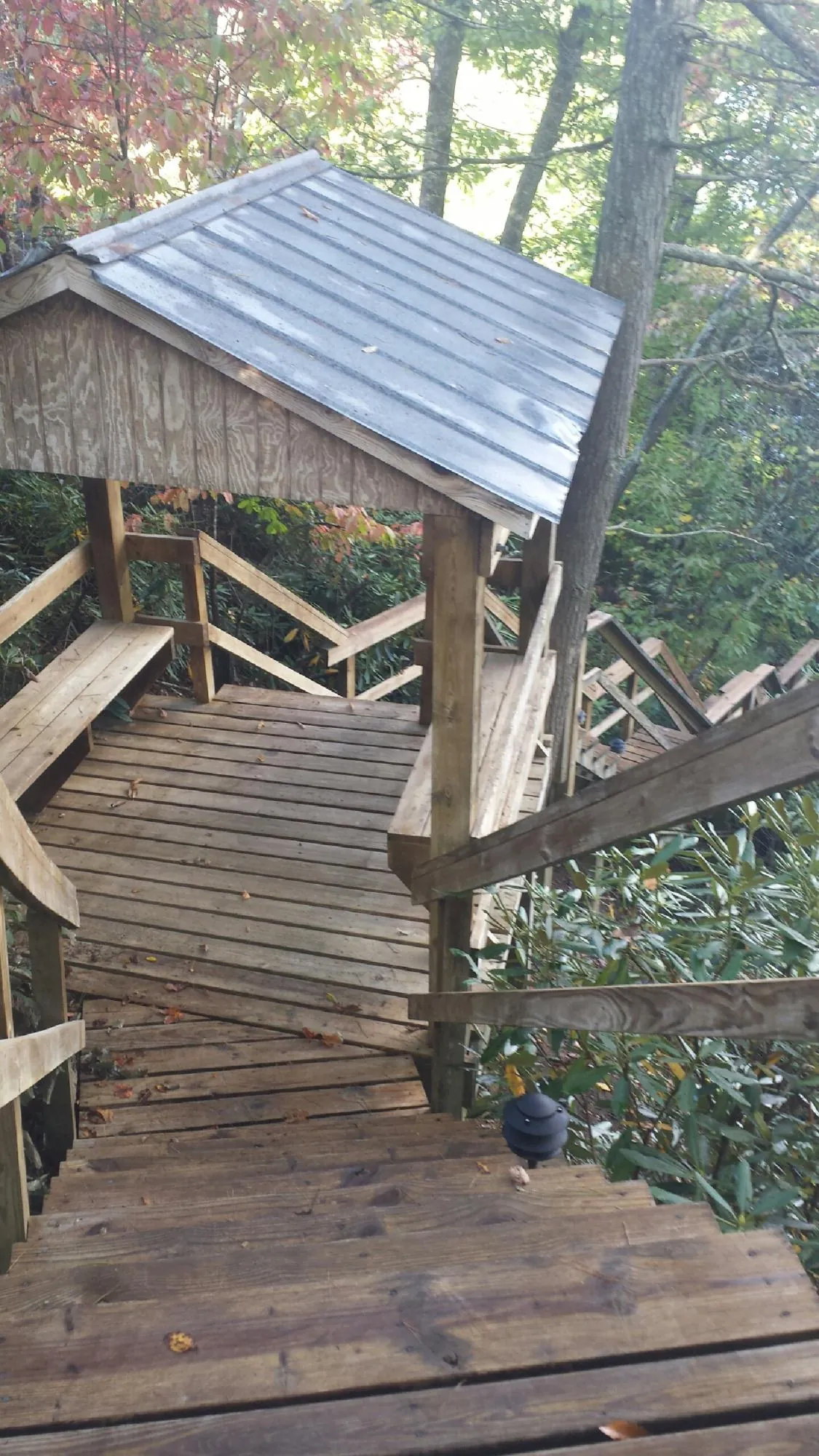 Metal roofed shelter over wooden steps on a wooded walkway — Skylight Repair & Installation work by our crew in Staples