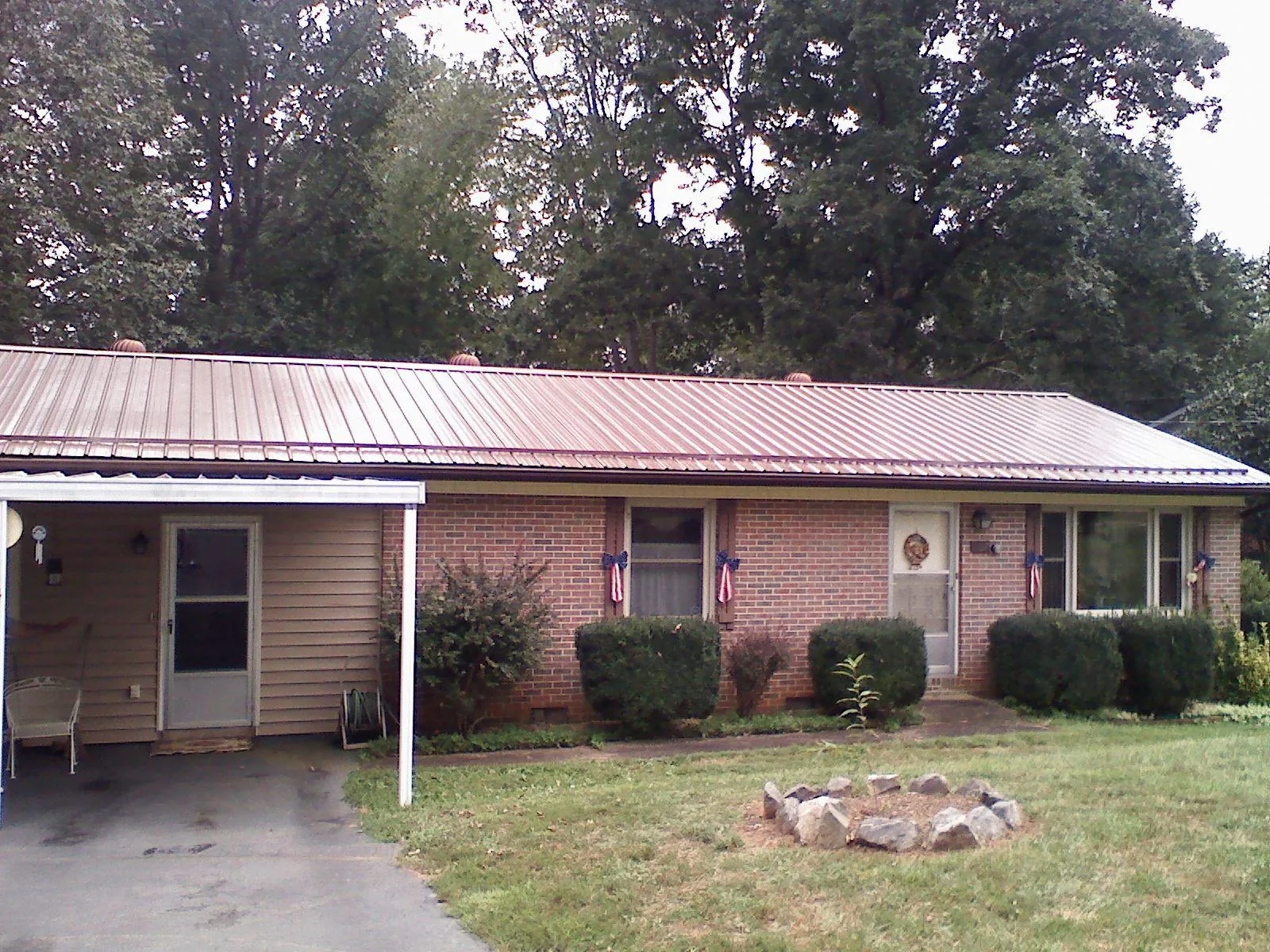 Bronze metal roof and carport on a brick ranch home — Roof Repair work by our crew in Staples