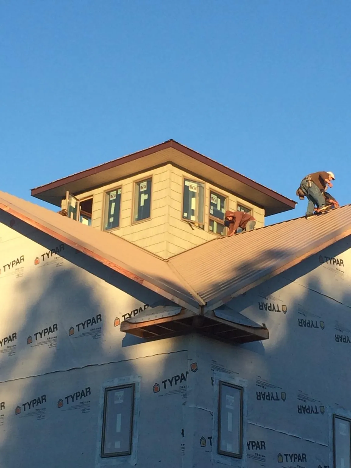 Roofers working around a rooftop cupola on a new metal roof at sunset — Roof Waterproofing in Staples by Roofing Brothers